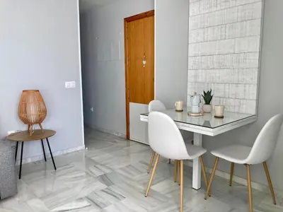 a dining room with a table and white chairs at ÁTICO VALDELAGRANA PLAYA - Aire Acondicionado y Piscina in El Puerto de Santa María