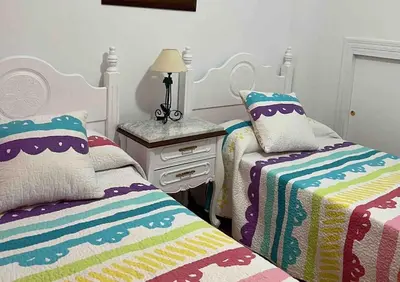 a bedroom with two beds and a table with a lamp at Casa duplex en chipiona in Chipiona