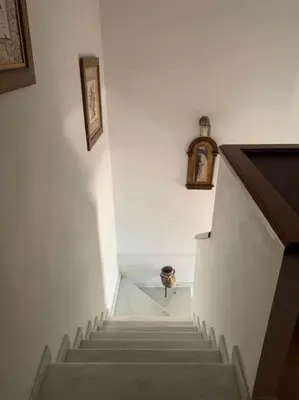 a stairway leading up to a room with a clock at Casa duplex en chipiona in Chipiona