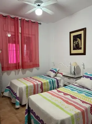 a bedroom with two beds and a ceiling fan at Casa duplex en chipiona in Chipiona