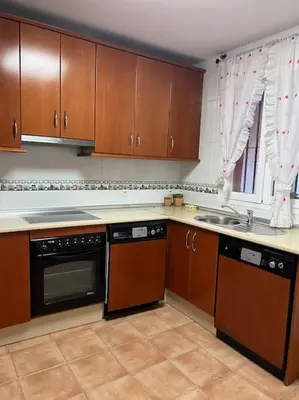 a kitchen with wooden cabinets and a stove top oven at Casa duplex en chipiona in Chipiona