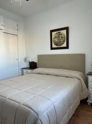 a white bed in a bedroom with a picture on the wall at Casa duplex en chipiona in Chipiona