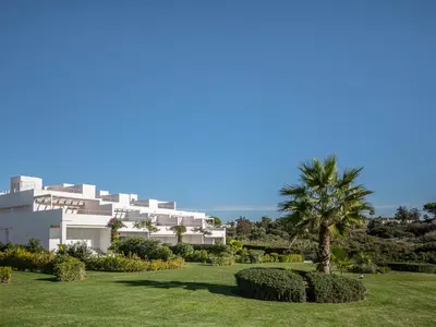 a large white building with a palm tree in a park at Villa Cristina by Interhome in Conil de la Frontera