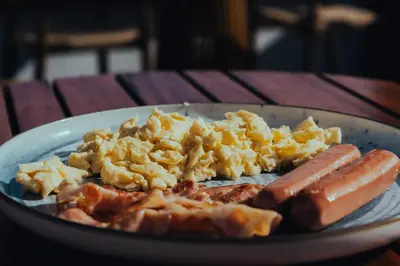 a plate of breakfast food with sausage and eggs at esZentrico Suites Jerez in Jerez de la Frontera