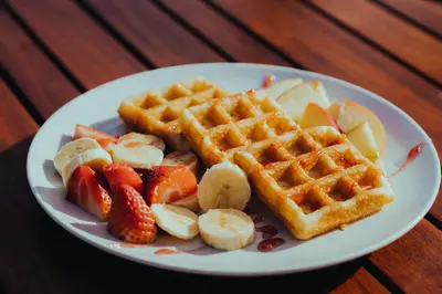 a plate of waffles and fruit on a table at esZentrico Suites Jerez in Jerez de la Frontera
