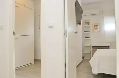 a white kitchen with a refrigerator and a bed at Apartamento Madrid in Cádiz