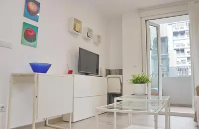 a white living room with a tv and a table at Apartamento Madrid in Cádiz