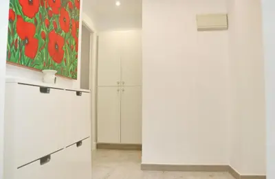a kitchen with white cabinets and a painting on the wall at Apartamento Madrid in Cádiz