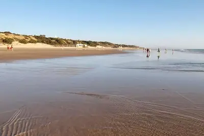 a group of people walking on the beach at Novo Sancti Petri, La Barrosa, 2 Beds Room Apartamento by Chiclana Dreams in Chiclana de la Frontera