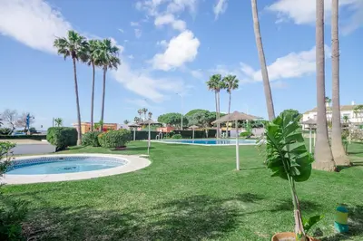 a park with a swimming pool and palm trees at Laja Bermeja, piscina y primera línea de La Barrosa in Chiclana de la Frontera