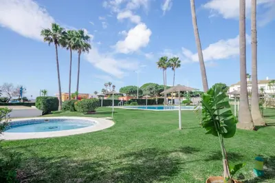 a park with a swimming pool and palm trees at Laja Bermeja, piscina y primera línea de La Barrosa in Chiclana de la Frontera