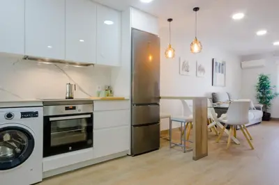 a kitchen with a refrigerator and a table with chairs at Laja Bermeja, piscina y primera línea de La Barrosa in Chiclana de la Frontera