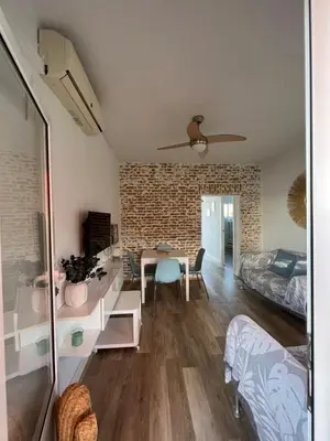 a living room with a table and a bedroom at Precioso Apto con vistas al Parque Nacional Doñana in Chipiona