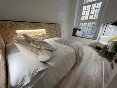 a bedroom with a bed with white sheets and pillows at Patiovecino Apartment Centro de Cádiz in Cádiz