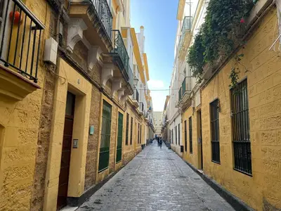 an empty alley in a city with yellow buildings at Patiovecino Apartment Centro de Cádiz in Cádiz