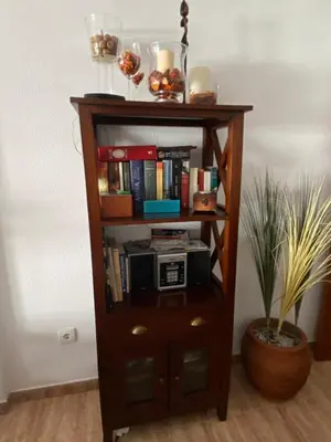 a book shelf filled with books and a microwave at Apartamento a unos pasos de la Playa (Rota) in Rota