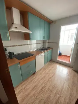 a kitchen with blue cabinets and a wooden floor at Apartamento a unos pasos de la Playa (Rota) in Rota