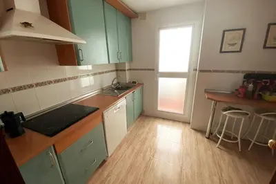 a kitchen with green cabinets and a wooden floor at Apartamento a unos pasos de la Playa (Rota) in Rota