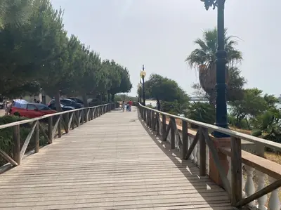 a wooden bridge with a person walking on it at Apartamento a unos pasos de la Playa (Rota) in Rota