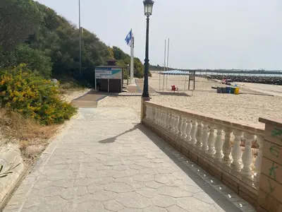 a sidewalk next to a beach with a street light at Apartamento a unos pasos de la Playa (Rota) in Rota