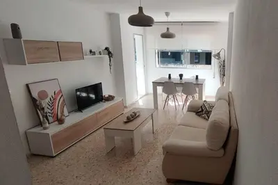 a living room with a couch and a tv and a table at Amplio apartamento junto a la Playa Victoria in Cádiz