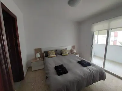 a bedroom with a large bed with two bags on it at Amplio apartamento junto a la Playa Victoria in Cádiz
