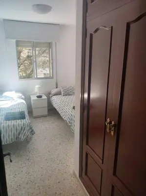a bedroom with two twin beds and a door at Amplio apartamento junto a la Playa Victoria in Cádiz