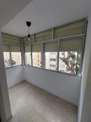 an empty room with large windows in a building at Amplio apartamento junto a la Playa Victoria in Cádiz