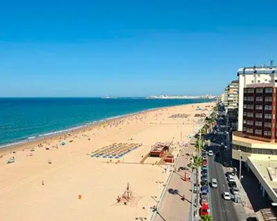 a beach with a lot of people and the ocean at Amplio apartamento junto a la Playa Victoria in Cádiz