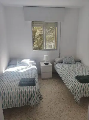 a bedroom with two beds and a window at Amplio apartamento junto a la Playa Victoria in Cádiz