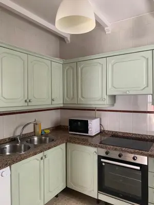 a kitchen with white cabinets and a sink and a microwave at Piso coqueto céntrico en Jerez (San Miguel) in Jerez de la Frontera