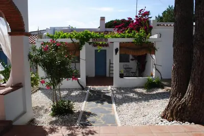 a white house with a blue door and flowers at CÁDIZ - GANESHA acogedor apartamento en Chiclana de la Frontera, España in Chiclana de la Frontera