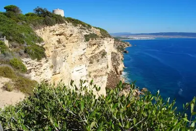 a cliff with a lighthouse on top of the ocean at CÁDIZ - GANESHA acogedor apartamento en Chiclana de la Frontera, España in Chiclana de la Frontera