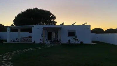 a white house with a sunset in the background at Casa Costa Ecologica y de Design con Piscina, Jardin y Parking in Chiclana de la Frontera