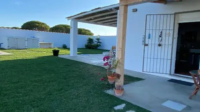 a white house with a door and a grass yard at Casa Costa Ecologica y de Design con Piscina, Jardin y Parking in Chiclana de la Frontera