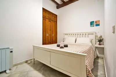 a white bedroom with a bed with a dresser at Apartamento Casa Palacio 1890. in El Puerto de Santa María