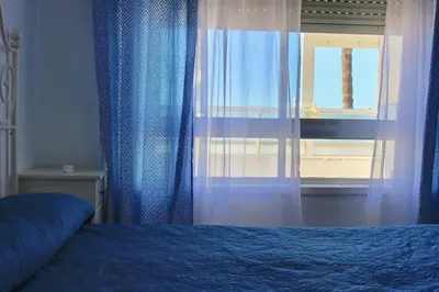a bedroom with a bed and a window with curtains at AranPe PLAYA CÁDIZ in Cádiz