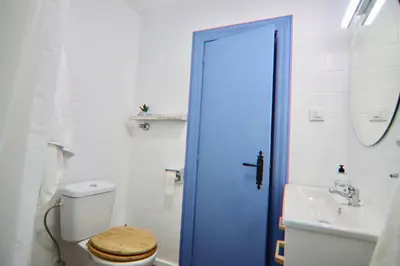 a bathroom with a toilet with a blue shower door at AranPe PLAYA CÁDIZ in Cádiz