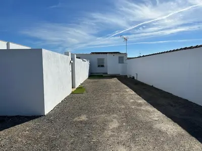a white fence and a white wall with a driveway at Sumatra Chalet in Chiclana de la Frontera