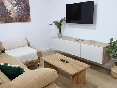 a living room with a couch and a tv on a wall at Sumatra Chalet in Chiclana de la Frontera