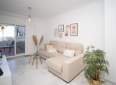 a living room with a couch and two potted plants at SibsSanlucar Donana 1ª Línea Playa-Piscina-Padel in Sanlúcar de Barrameda