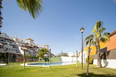 a park with a swimming pool in front of a building at SibsSanlucar Donana 1ª Línea Playa-Piscina-Padel in Sanlúcar de Barrameda