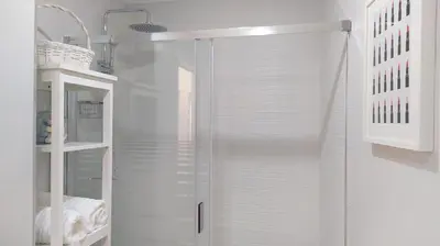 a glass shower stall in a white bathroom with white shelves at Sherryflat Porvenir in Jerez de la Frontera
