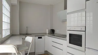 a white kitchen with white appliances and a table and chairs at Sherryflat Porvenir in Jerez de la Frontera