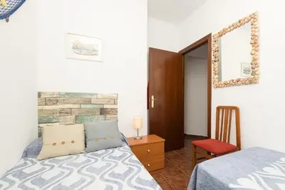 a bedroom with a bed and a chair and a mirror at El Deseo in Chiclana de la Frontera