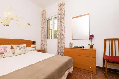 a bedroom with a bed and a mirror and a chair at El Deseo in Chiclana de la Frontera