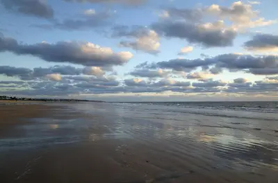 a beach with a cloudy sky and the ocean at El Deseo in Chiclana de la Frontera