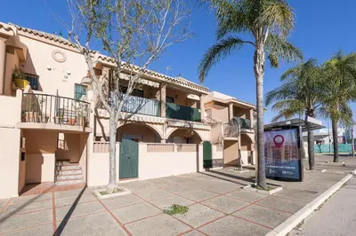 a building with palm trees on a street at El Deseo in Chiclana de la Frontera