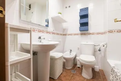 a white bathroom with a sink and a toilet at El Deseo in Chiclana de la Frontera