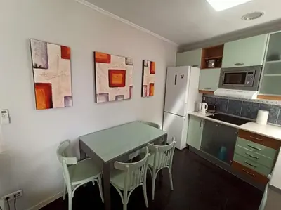 a kitchen with a table and chairs and a refrigerator at ÁTICO SANTA MARÍA in Cádiz